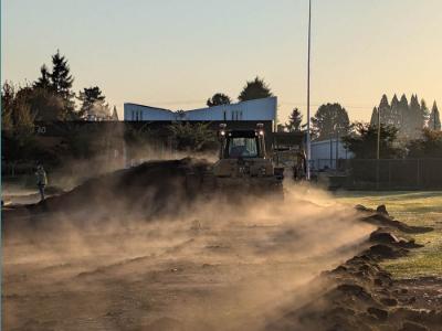 A bulldozer pushes a pile of dirt on the Chemeketa baseball field.